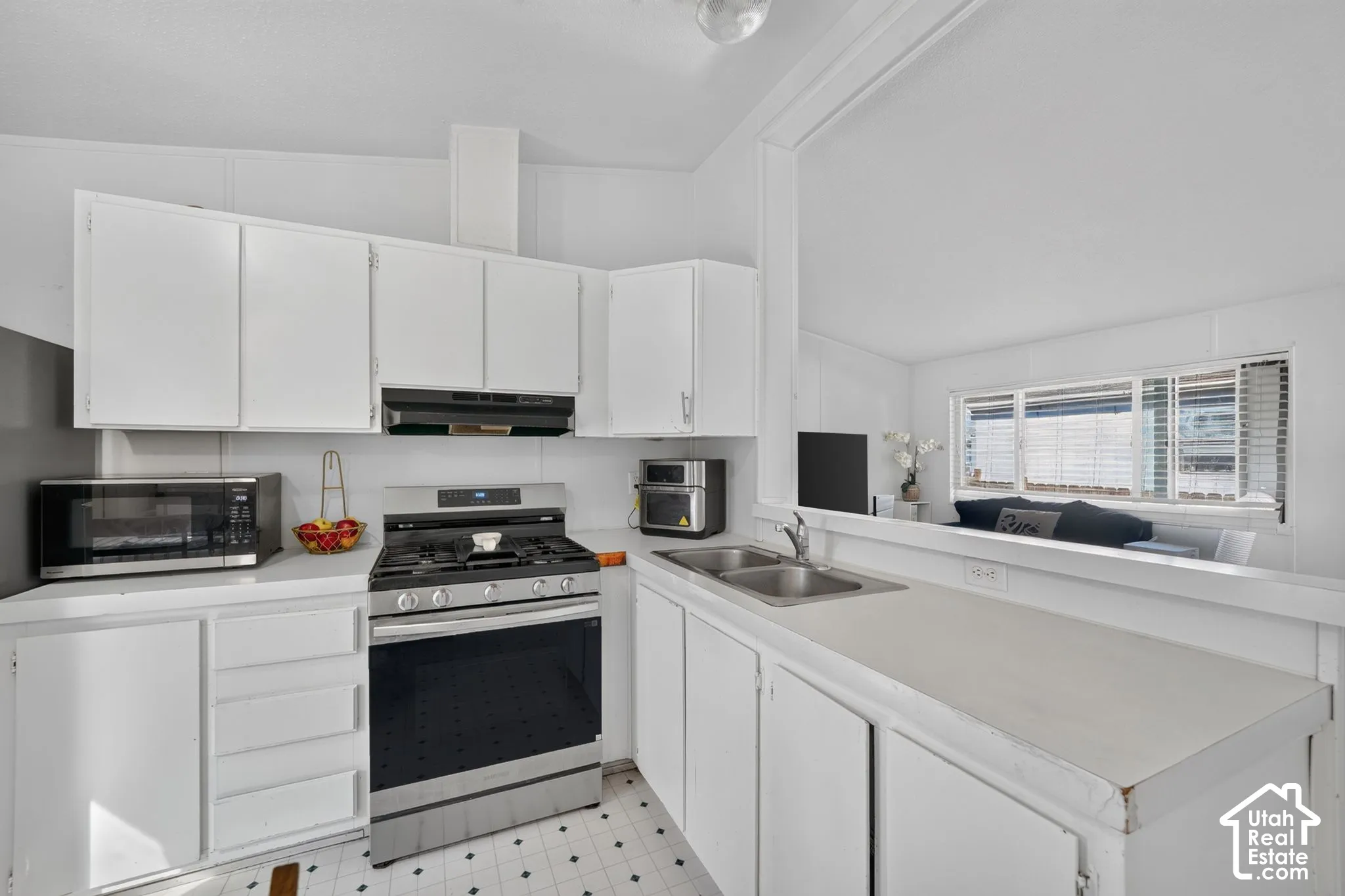 White cabinetry, stainless steel range, dual basin sink, and ample countertop space