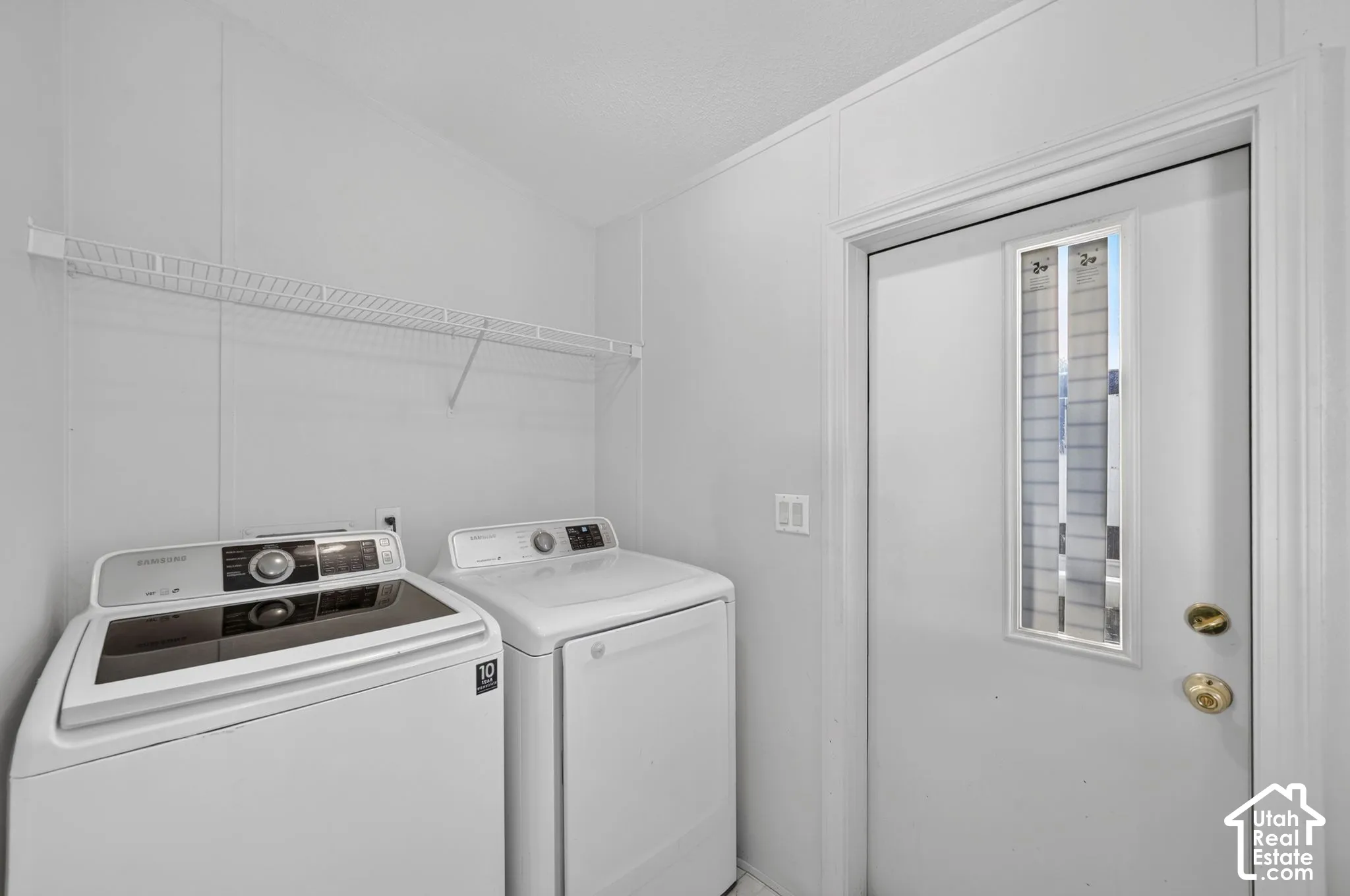 Laundry area featuring a white wire shelf, a white door with a window insert, and brass-tone hardware