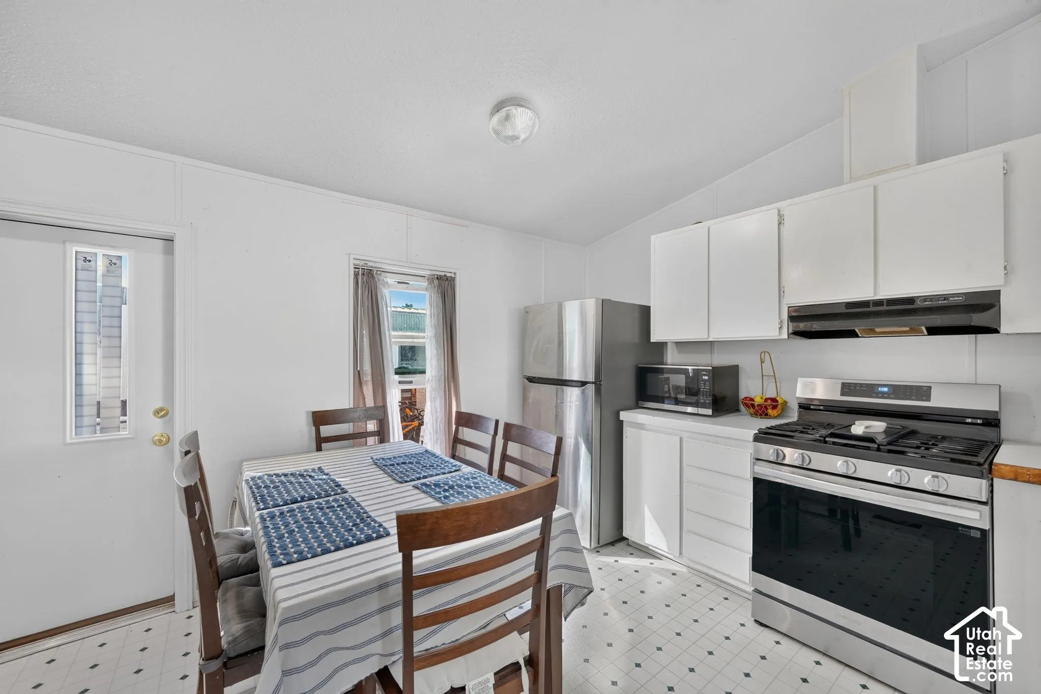 Kitchen with white cabinetry, stainless steel gas range, and patterned flooring