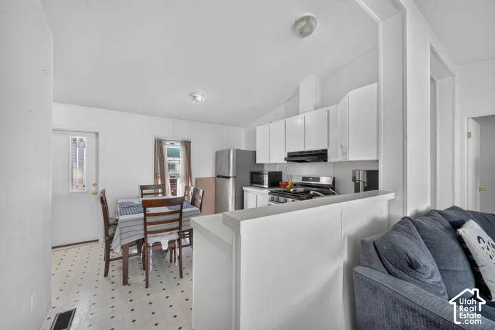 Kitchen featuring white cabinetry, stainless steel appliances, and a gas range