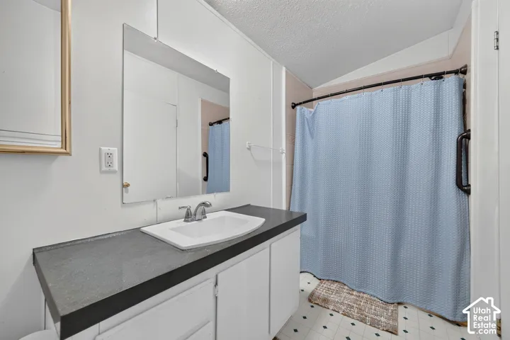 Built-in vanity with a single basin sink, wall-mounted mirror, and tile flooring