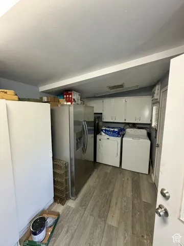 Laundry area featuring wood-finish flooring and white cabinetry