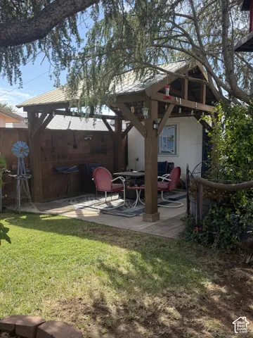 Expansive green lawn with a paved patio featuring a wood pergola and a built-in outdoor structure