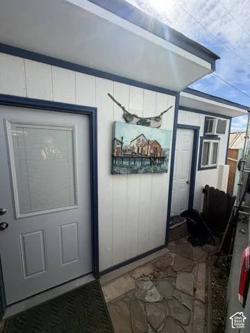 White paneled exterior with contrasting blue trim, two exterior doors, and a natural stone-finish pathway