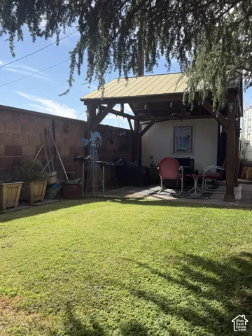 Expansive grassy yard with a paver patio and a wood-framed pergola featuring a metal roof