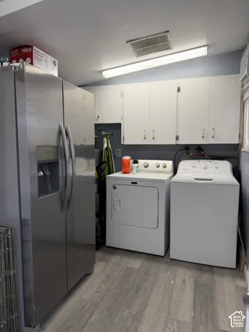 Wood-finish flooring with white upper cabinetry and a ceiling-mounted fluorescent light fixture