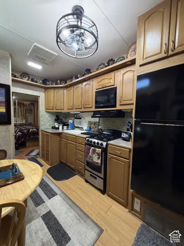 Wood-finish flooring with a full kitchen featuring a stainless steel gas range, built-in microwave, and wood cabinetry