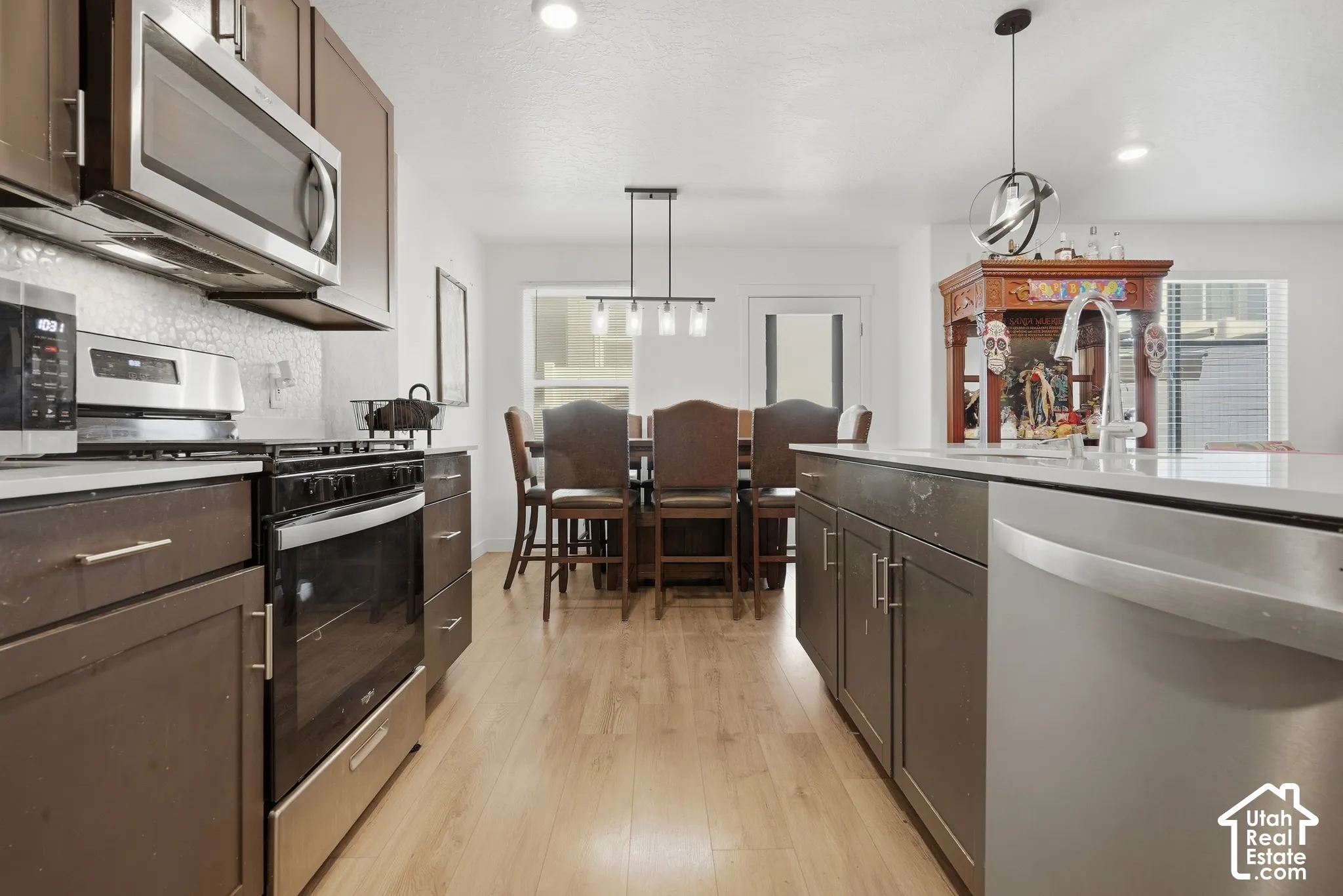 Stainless steel appliances, wood-finish flooring, dark wood cabinetry, white countertops, and recessed lighting