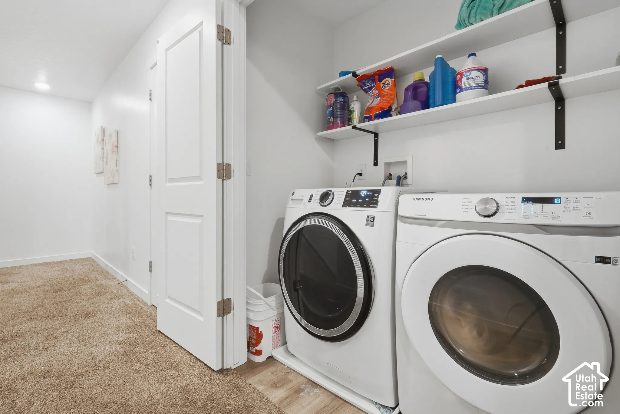 Dedicated laundry area featuring a washer and dryer, wood-finish flooring, and wall-mounted shelving
