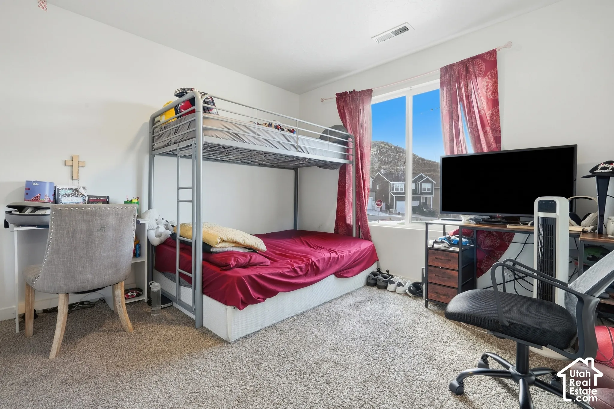 Carpeted bedroom featuring a large window, white walls, and a recessed ceiling vent