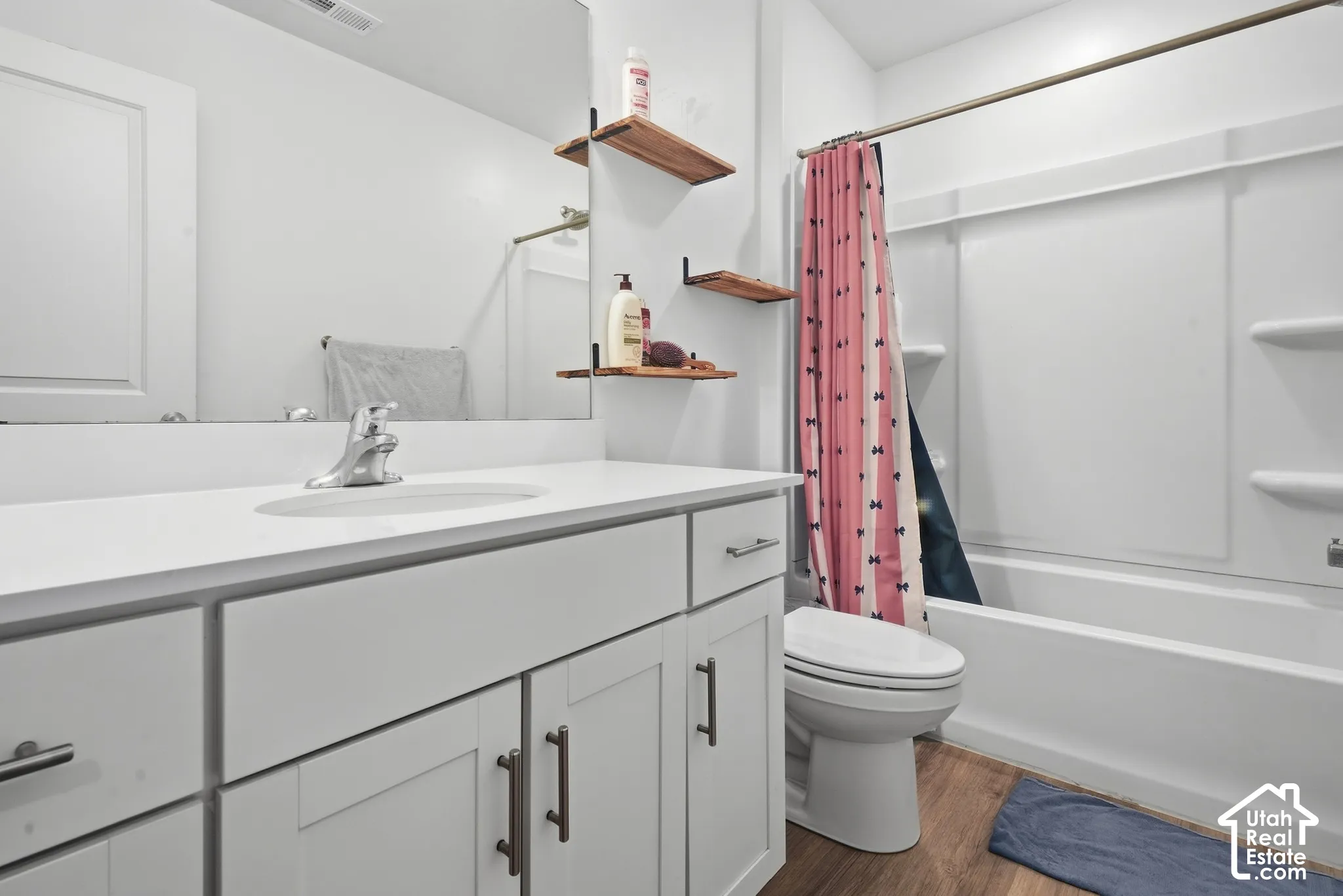 White vanity with shaker-style cabinetry, a white countertop, and an integrated sink
