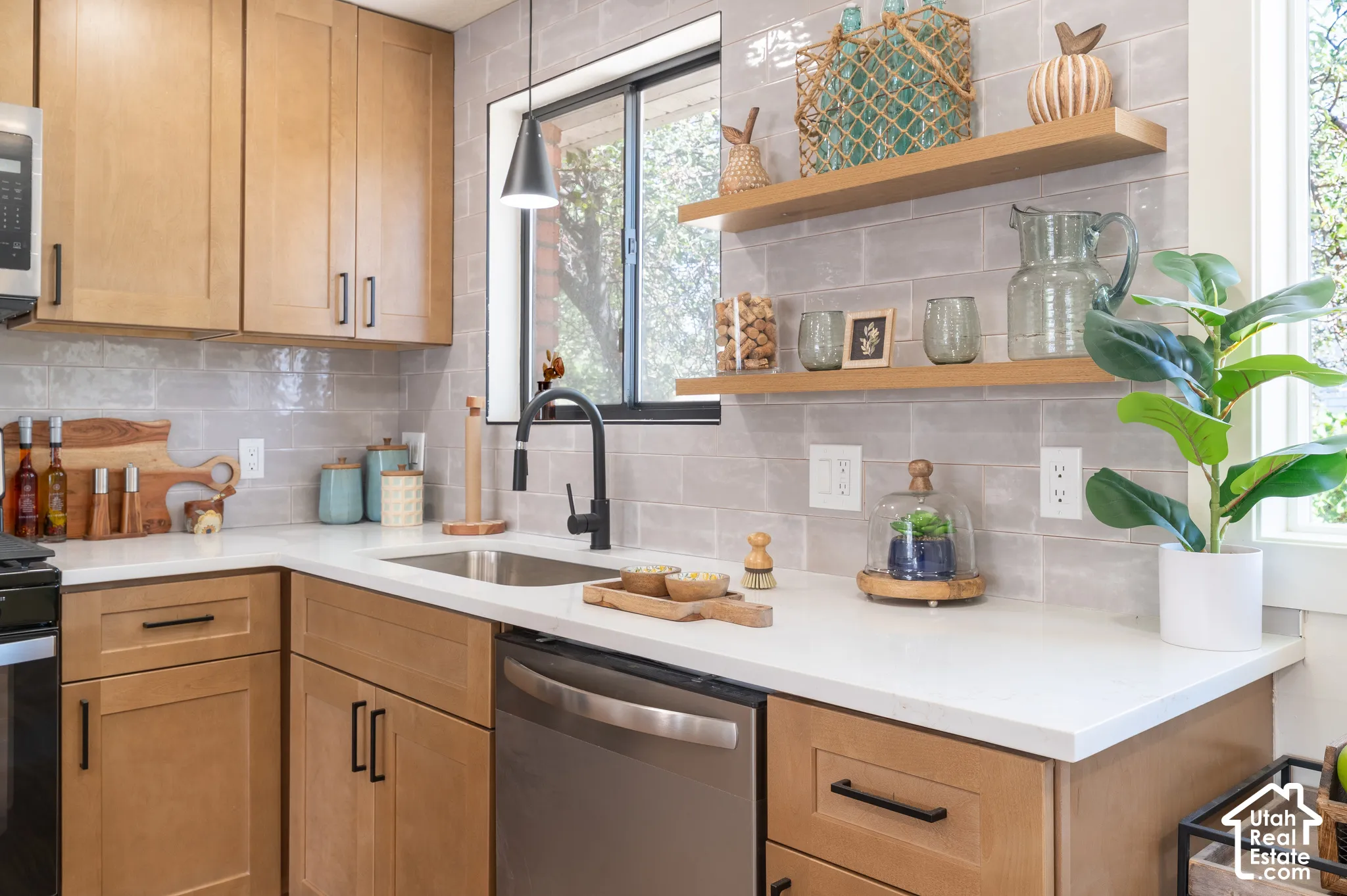Hardwood cabinetry, light-toned countertops, a matte black faucet, and a light-grey subway tile backsplash