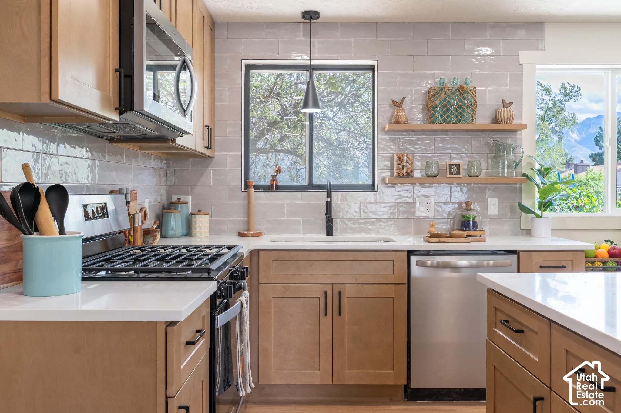 Kitchen featuring light wood-finish cabinetry, stainless steel appliances, white countertops, and a subway tile backsplash