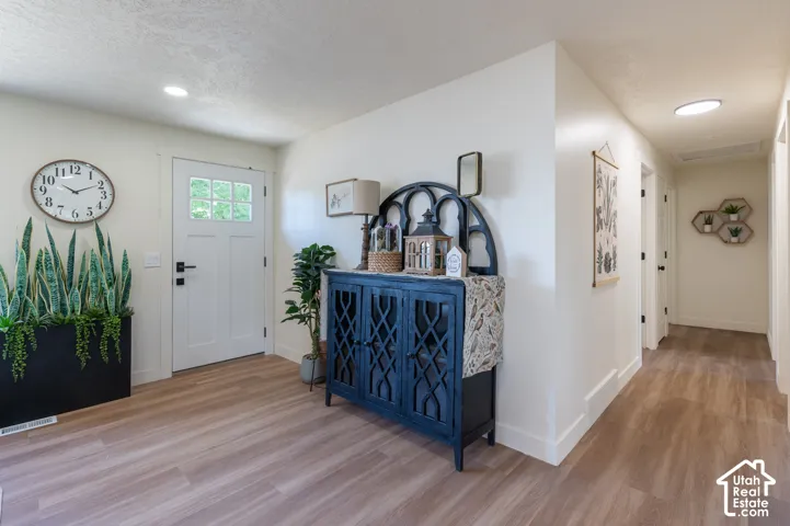 Entryway featuring wood-finish flooring, recessed lighting, and a white paneled door with glass inserts