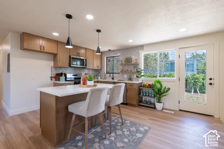 Kitchen featuring wood-finish flooring, recessed lighting, and an island with a light-toned countertop