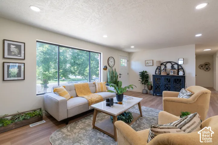 Recessed lighting, wood-finish flooring, large picture window, white paneled door with window, and smooth wall finishes