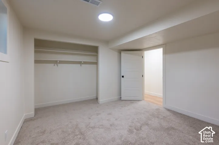 Recessed circular lighting, carpet flooring, built-in closet shelving, and a solid core door