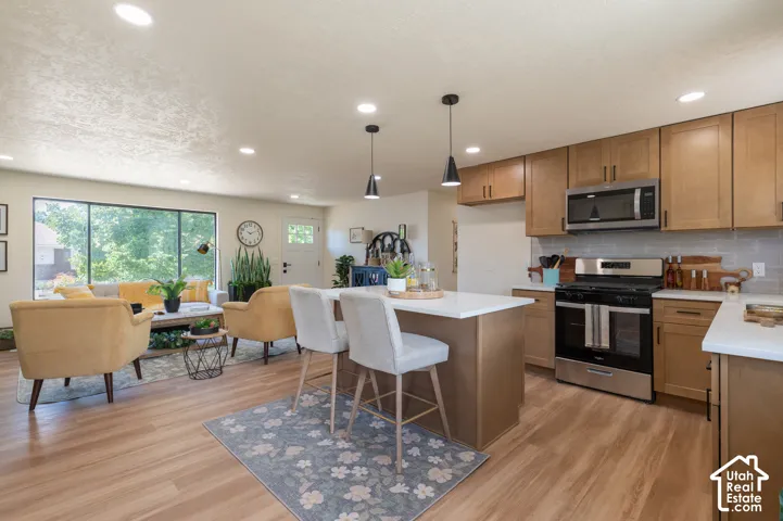 Open-concept living space featuring wood-finish flooring, recessed lighting, and a large picture window