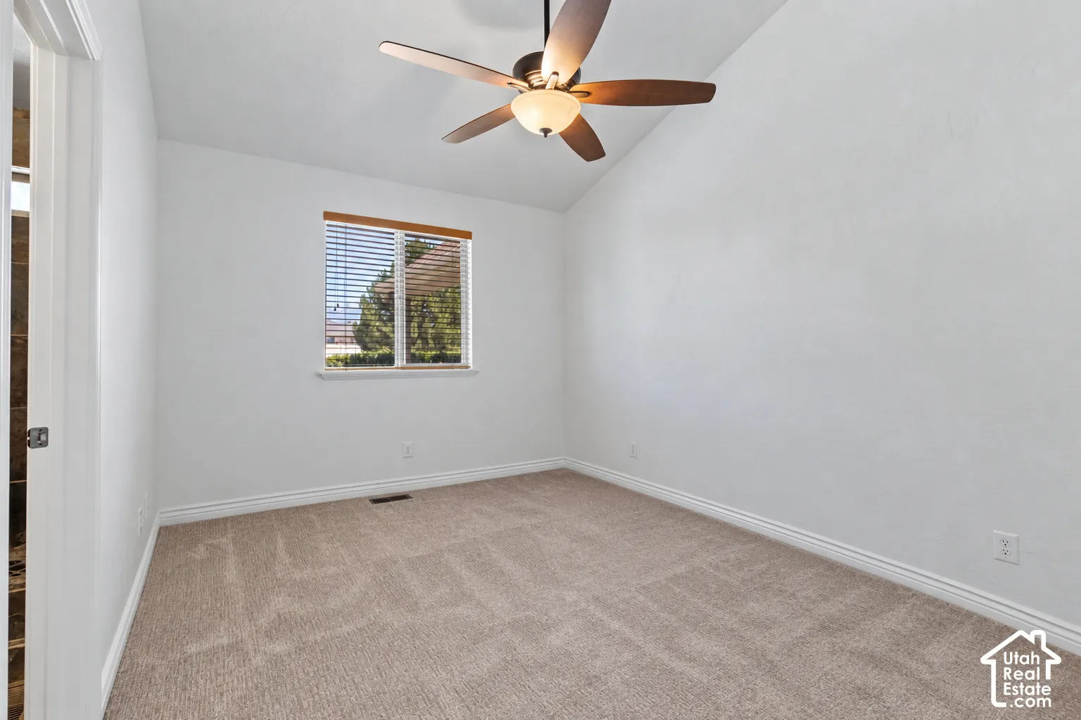 Vaulted ceiling featuring a ceiling fan with integrated lighting, a window with horizontal blinds, and neutral carpeting