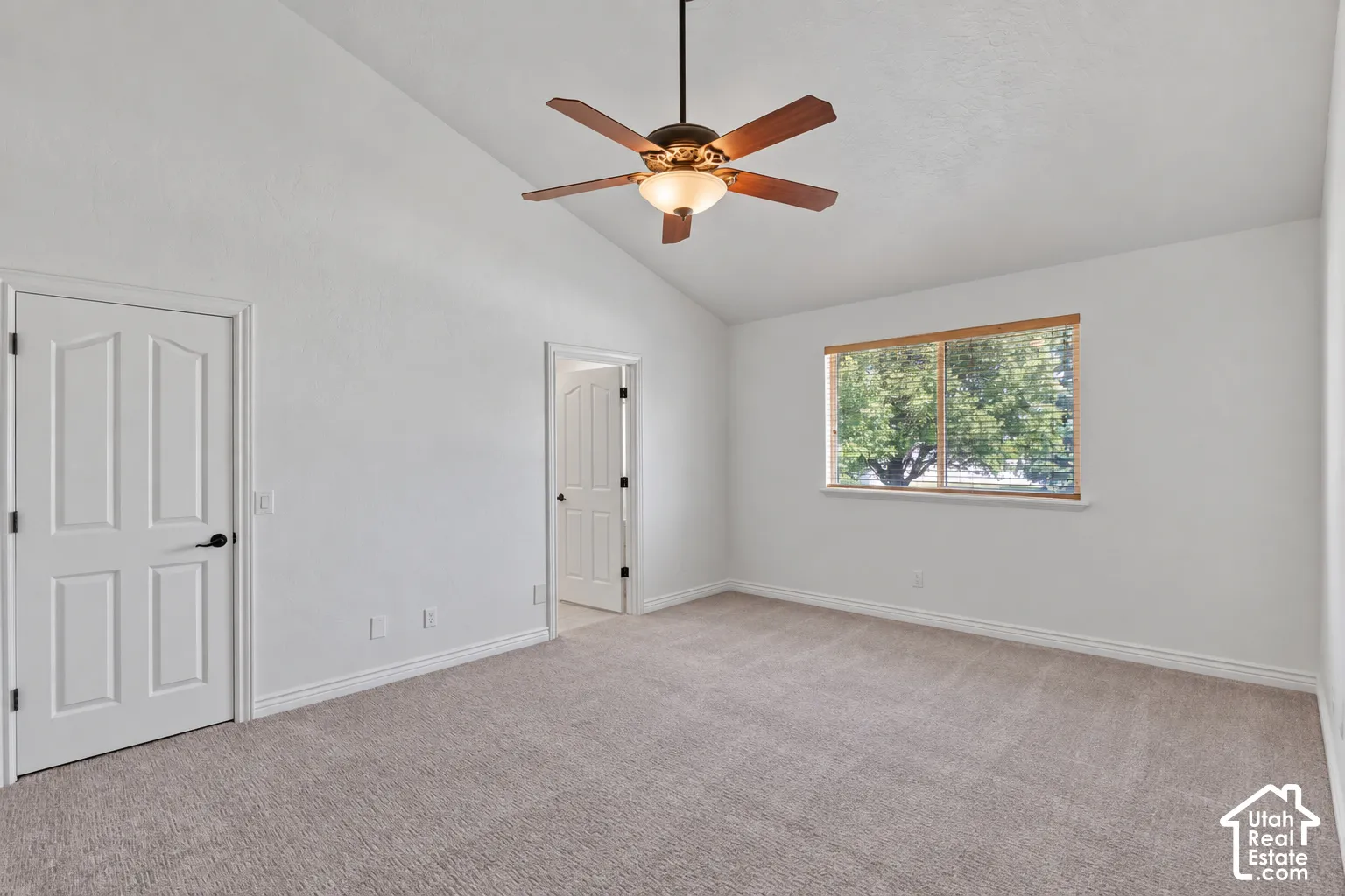 Vaulted ceiling with an integrated ceiling fan, light gray carpet, and white paneled doors