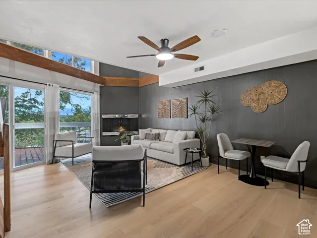 Hardwood-finish flooring throughout, featuring a fireplace with a decorative mantel, large glass sliding doors, and a wood-beamed ceiling