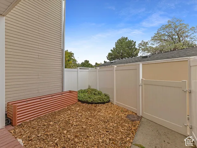 Private outdoor area featuring a tall privacy fence, wood chip ground cover, and an elevated corrugated planter box