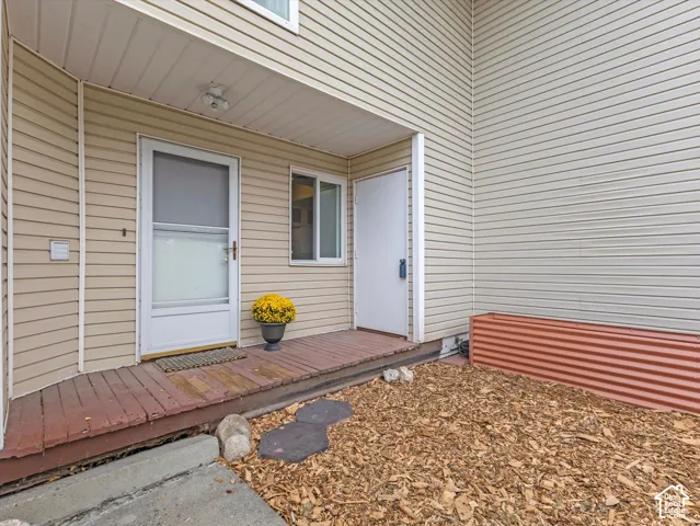 Entry with horizontal siding, a screen door, and a wooden porch