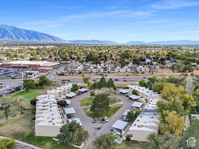 Multi-unit residential structures with covered parking, surrounded by mature trees and landscaped green areas