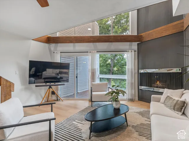 Vaulted ceilings with exposed wood beams, wood-finish flooring, built-in fireplace, and sliding glass doors
