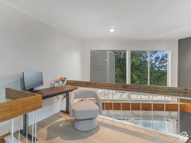 Open loft area featuring light wood-finish flooring, recessed lighting, and a white railing with a wood-finish handrail