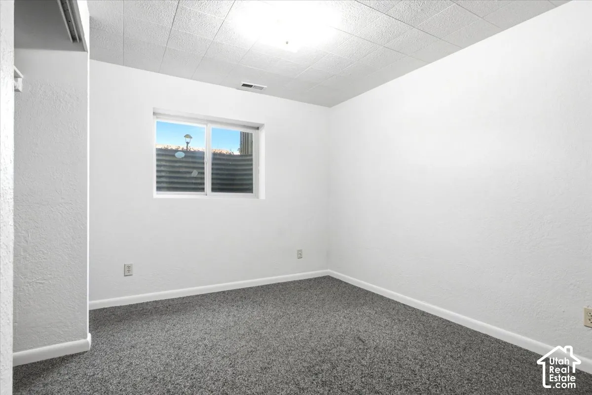 Recessed window with exterior well, white painted walls, textured ceiling, and gray carpeting