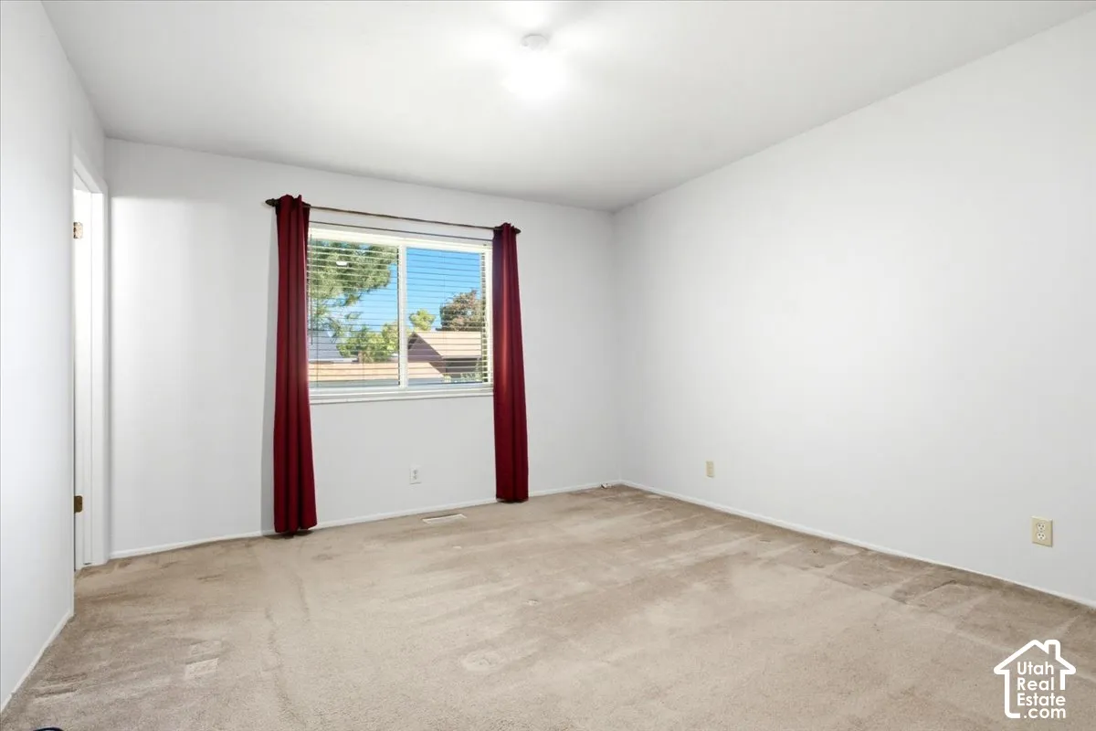 Master Bedroom Light-colored carpeting, white painted walls, and a single window with horizontal blinds