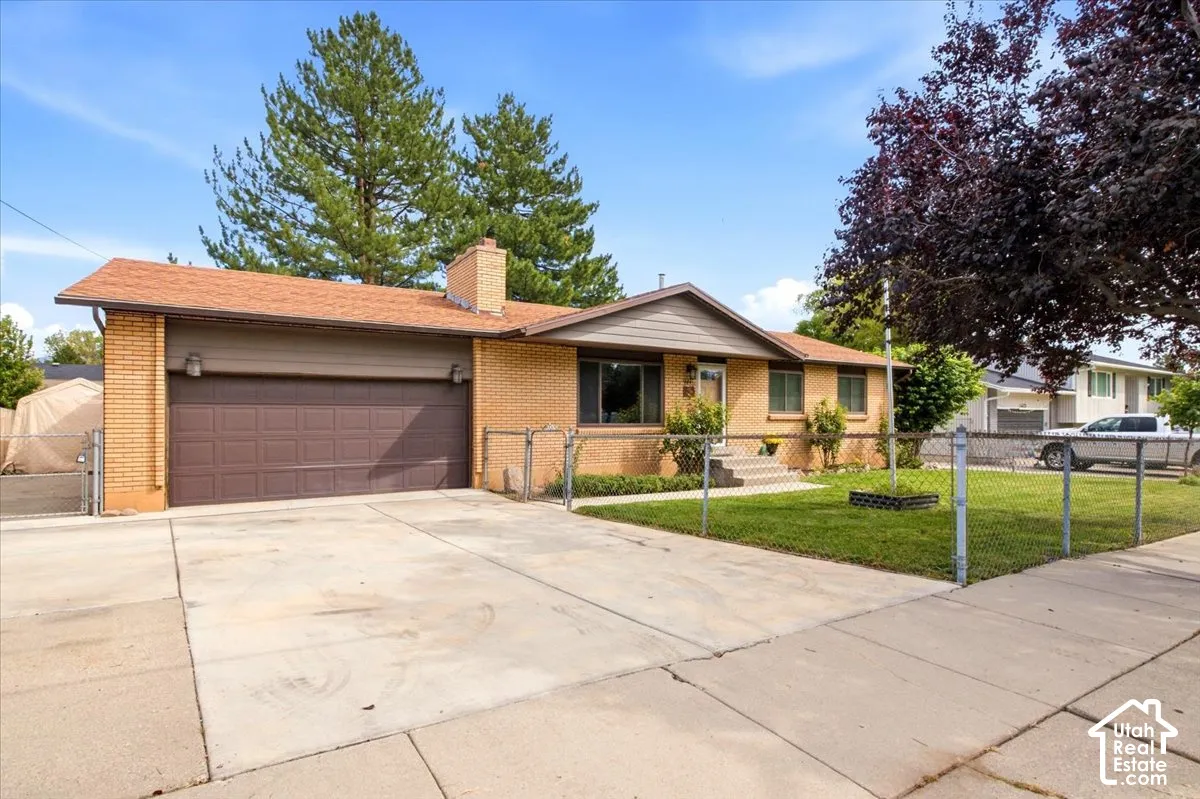 Brick exterior with a brown garage door, concrete driveway, and front lawn