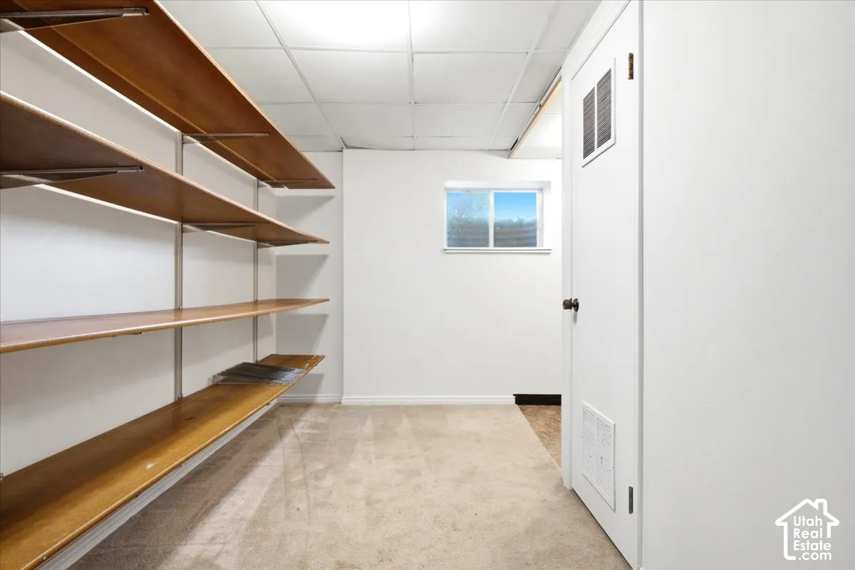 Extensive built-in shelving, white walls, drop ceiling, and a single window