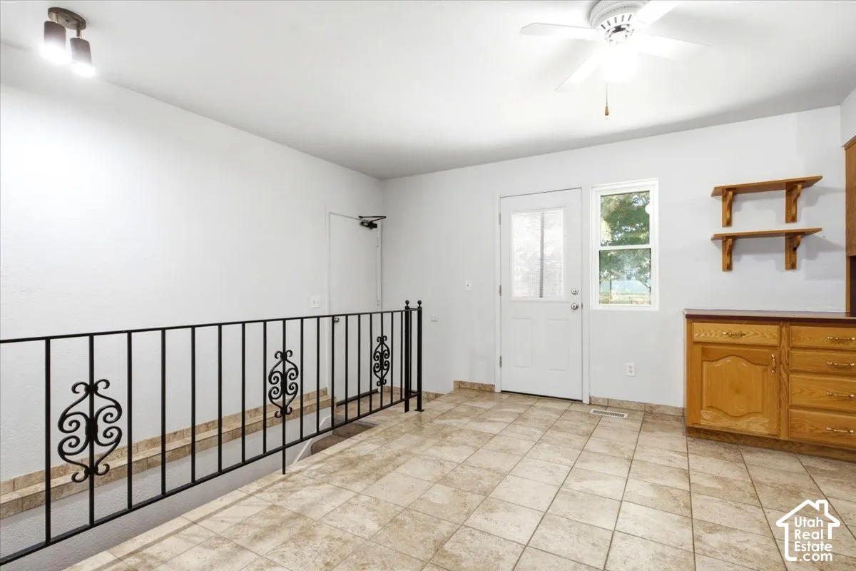 Tiled flooring with a contrasting dark railing, overhead ceiling fan, and built-in wood cabinetry with a countertop