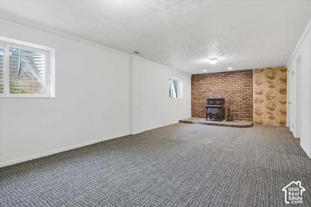 Spacious room with durable carpeting, a prominent brick accent wall, and a built-in hearth with an included stove