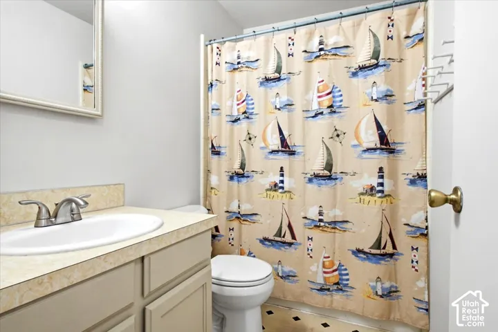 Main Level Bathroom featuring a vanity with an integrated sink, a two-handle faucet, a toilet, and patterned flooring
