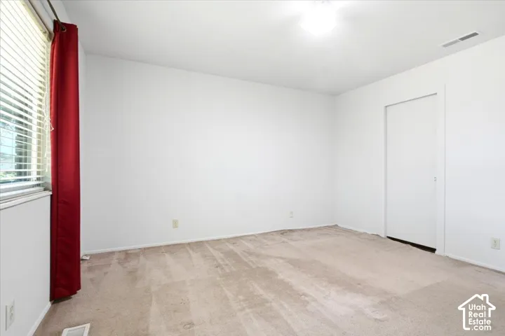 Master Bedroom Neutral tone wall paint, light-toned carpet flooring, horizontal window blinds, and a built-in closet with a sliding door