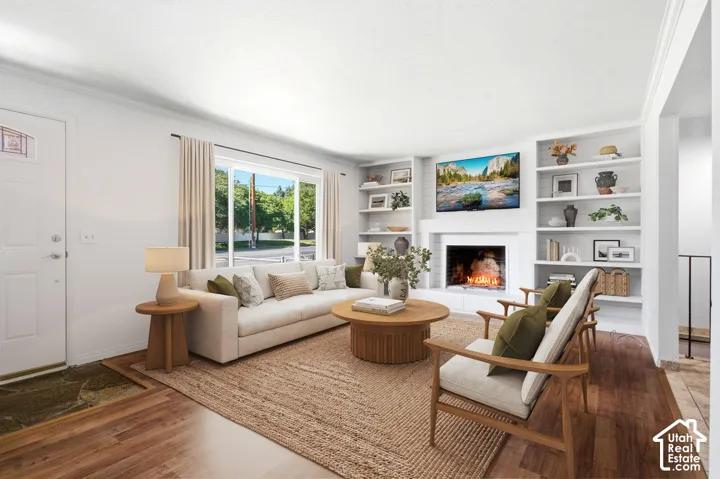 Living area with wood-finish flooring, a white paneled entry door, and a large window