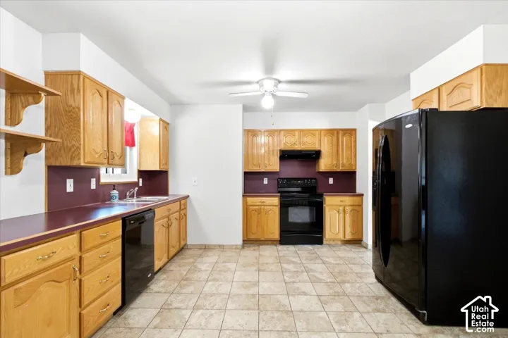 Kitchen featuring light wood cabinetry, a built-in dishwasher, tile flooring, and a ceiling fan