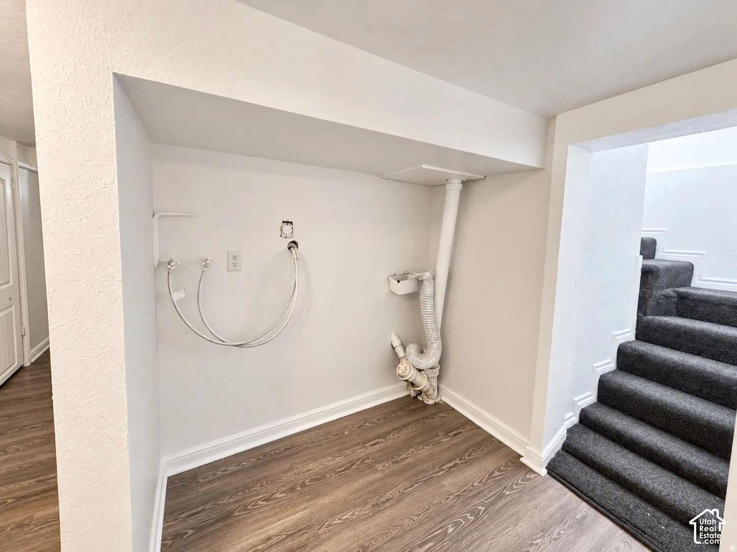 Dedicated laundry area featuring hookups for a washing machine and dryer, durable wood-finish flooring, and white trim molding