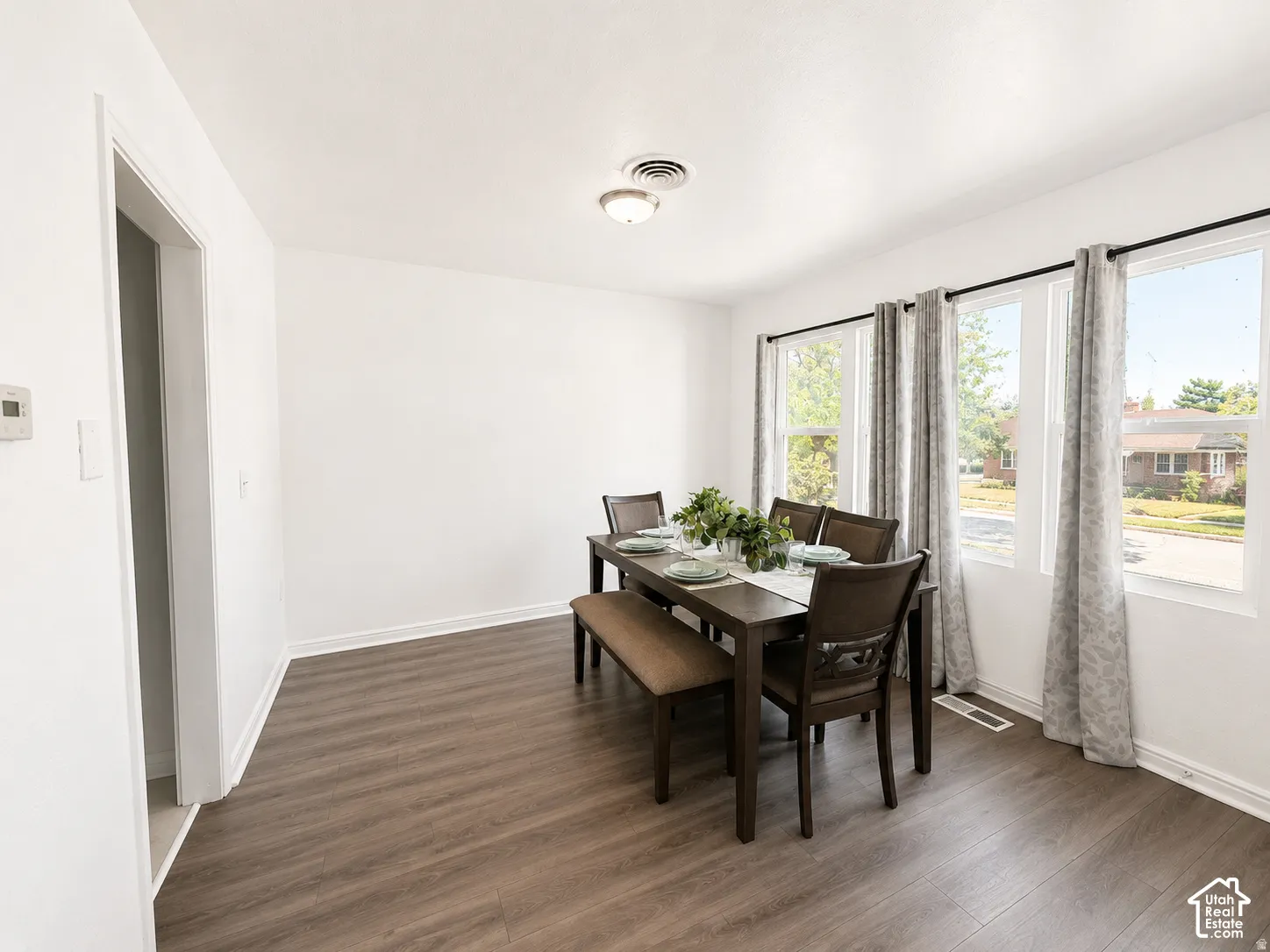 Wood-finish flooring, white walls, and multiple windows with white trim