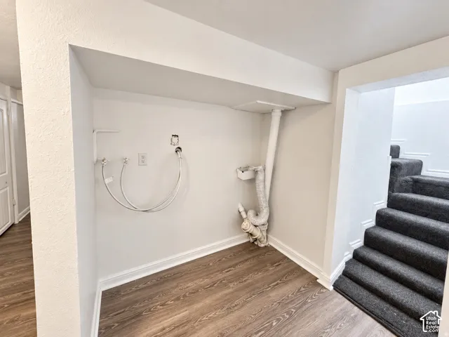 Dedicated laundry area featuring hookups for a washing machine and dryer, durable wood-finish flooring, and white trim molding