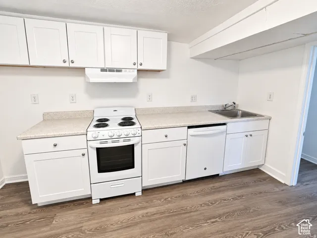 White cabinetry with brushed nickel hardware, white freestanding range, built-in dishwasher, and wood-finish flooring