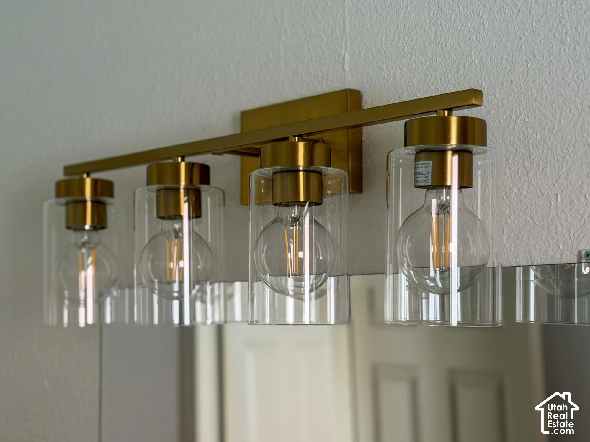 Modern four-light vanity fixture featuring a gold-tone finish and clear glass shades