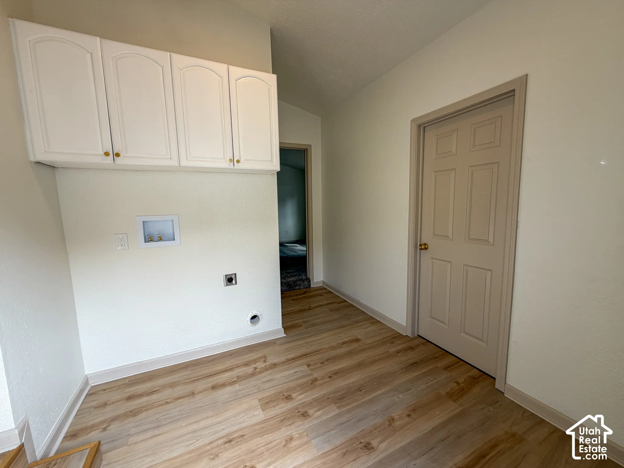 Wood-finish flooring, white walls, and built-in white cabinetry with gold-tone hardware