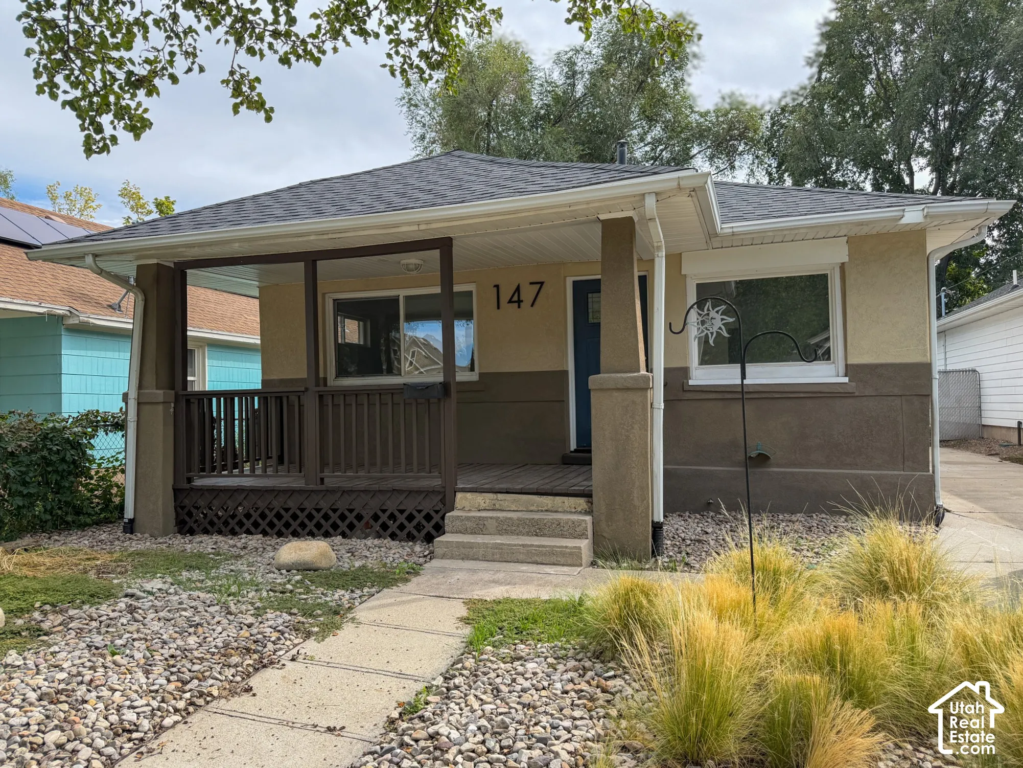 Stucco exterior with a covered porch, solid wood porch railing, and a stepped concrete walkway