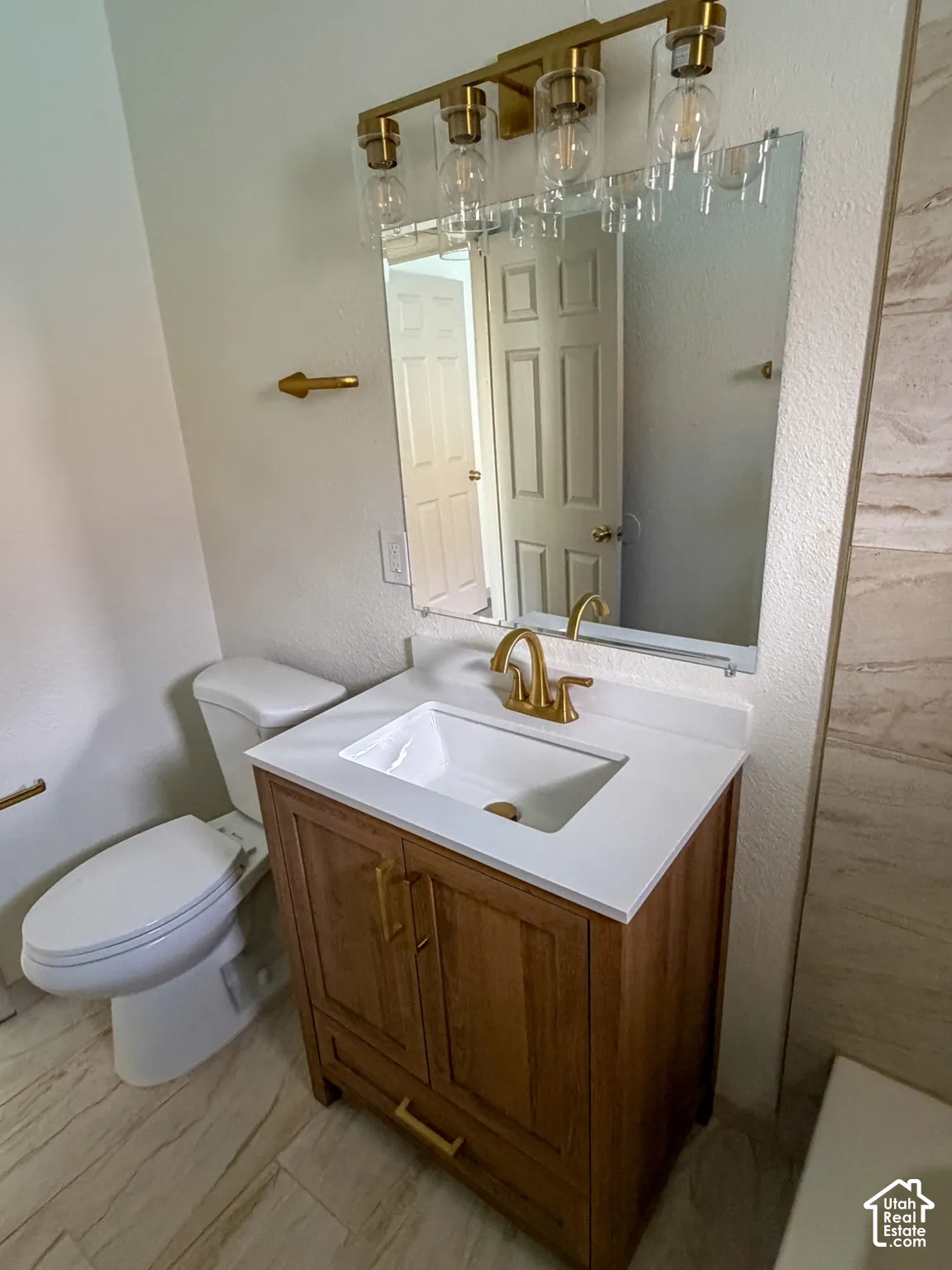Wood-finish vanity with white countertop, undermount sink, and gold-tone faucet