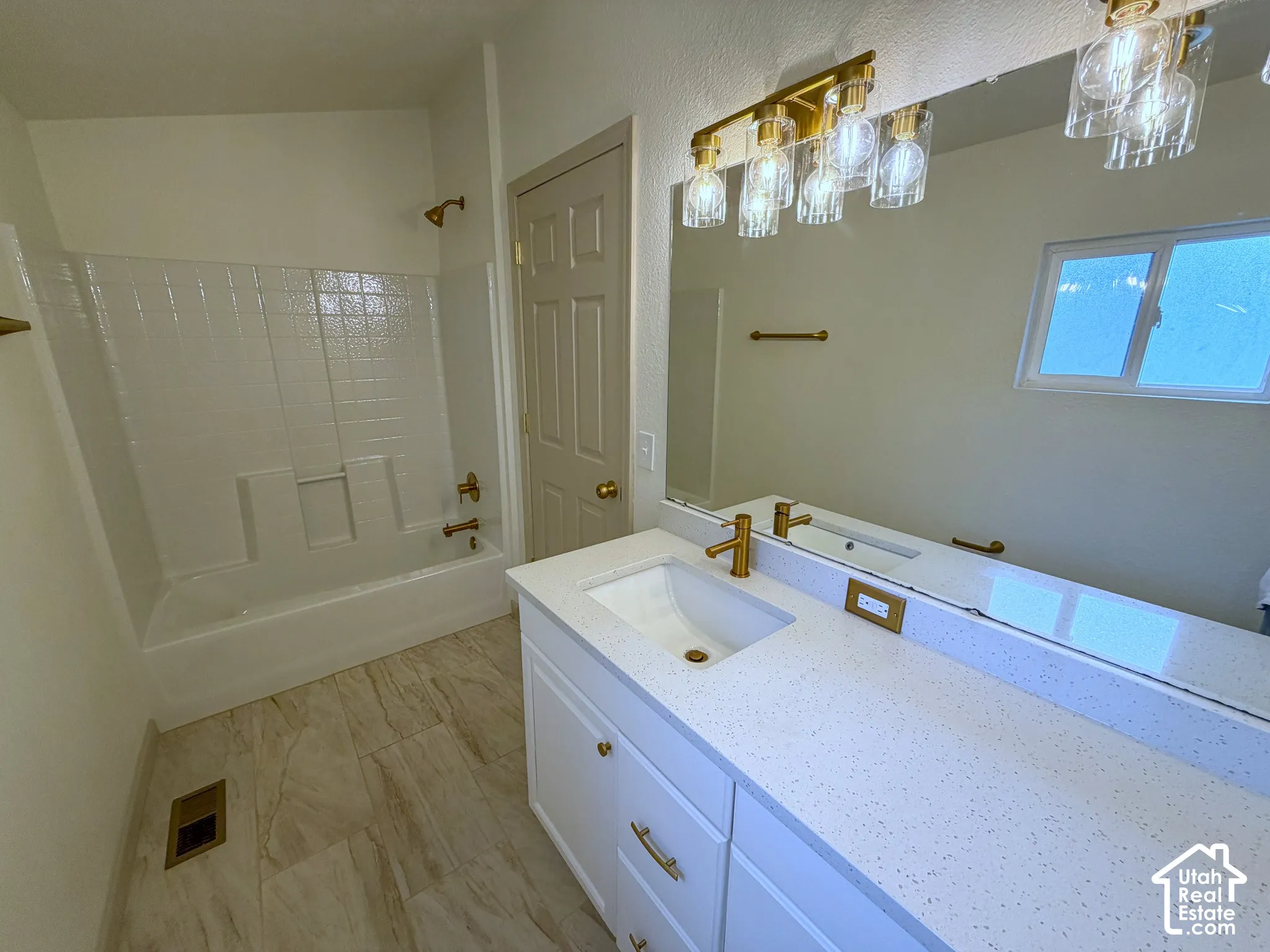 White vanity with gold-finish hardware, built-in sink, and speckled countertop