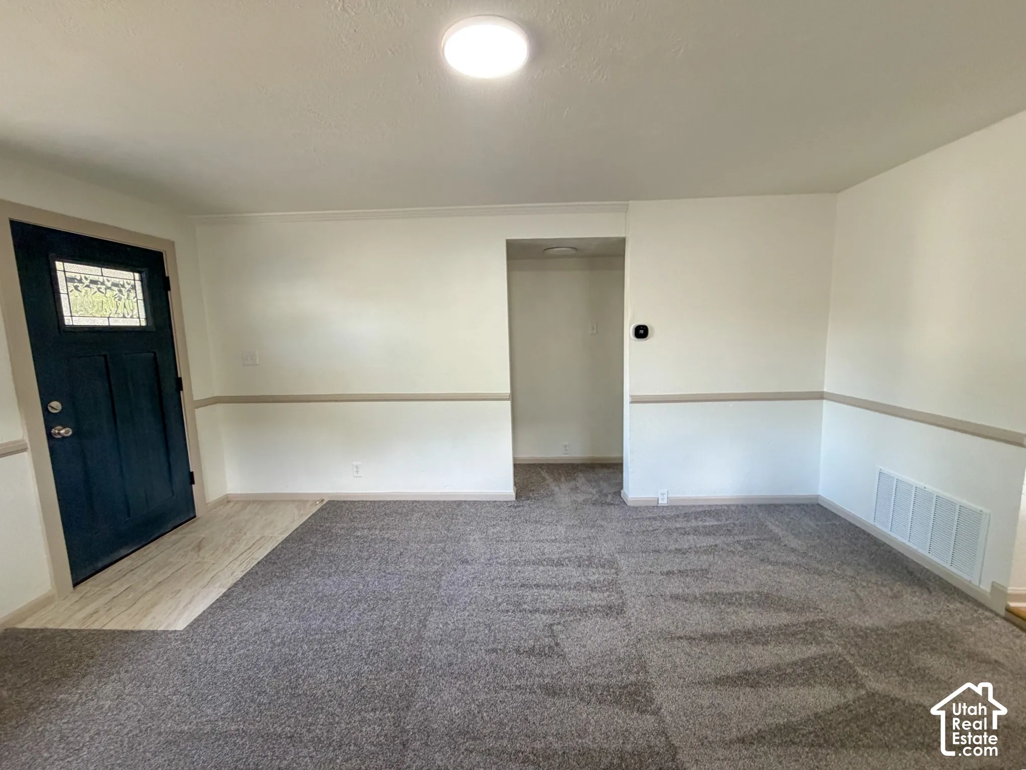 Recessed ceiling lighting, patterned carpet flooring, wood-finish flooring, two-tone wall treatment, and a dark-paneled front door with decorative glass